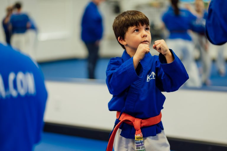 Young student in a guard stance looks up to his partner off camera.