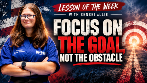 Graphic featuring Sensei Allie Peters in a blue martial arts gi alongside bold text reading "Lesson of the Week with Sensei Allie: Focus on the Goal, Not the Obstacle" over a road stretching toward a glowing target.