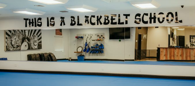 Krav Maga Martial Arts Dojo, looking at the mirrored wall. The phrase"This is a Blackbelt School" is spelt out above the mirrors in black vinyl.