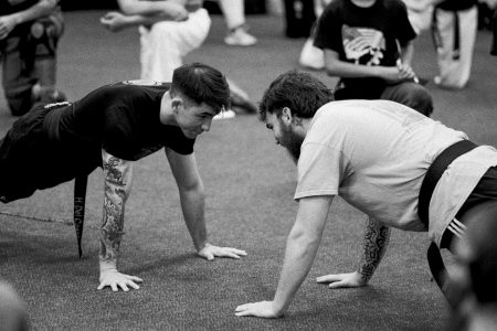 Black and white photo of Shihan Harley and Shihan Winston in a push-up position, facing each other.