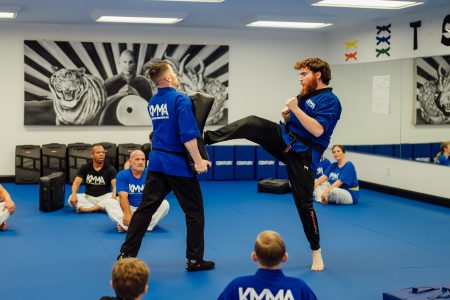In the Dojo, Shihan Winston kicking bag. Sensei Greg is holding.